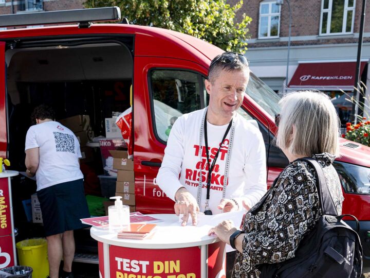 Billedet viser Diabetesforeningens sundhedsbus, hvor en af foreningens ansatte står og taler med en borger