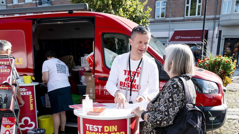 Billedet viser Diabetesforeningens sundhedsbus, hvor en af foreningens ansatte står og taler med en borger