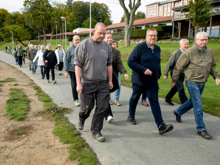 Billedet viser en gruppe mennesker der er glade og ude og gå tur på en vej