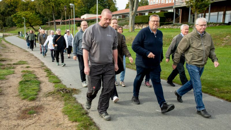 Billedet viser en gruppe mennesker der er glade og ude og gå tur på en vej