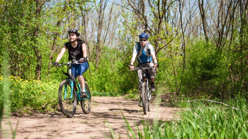 Billedet forestiller en mand og en kvinde, der cykler i naturen