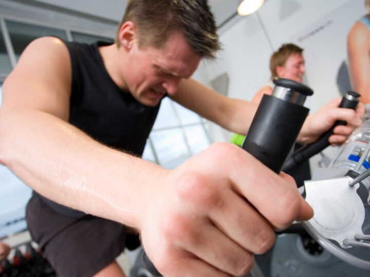 Mand sveder på motionscykel i træningslokale